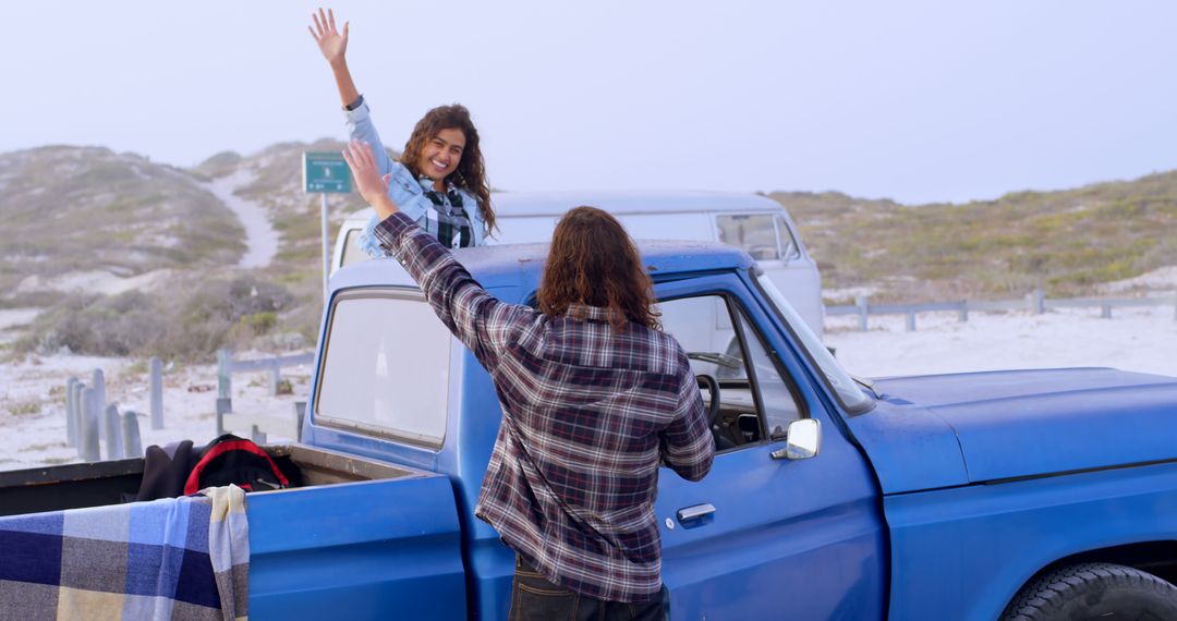 Young Man and Woman Waving by Blue Pickup Truck at Beach - Free Images, Stock Photos and Pictures on Pikwizard.com