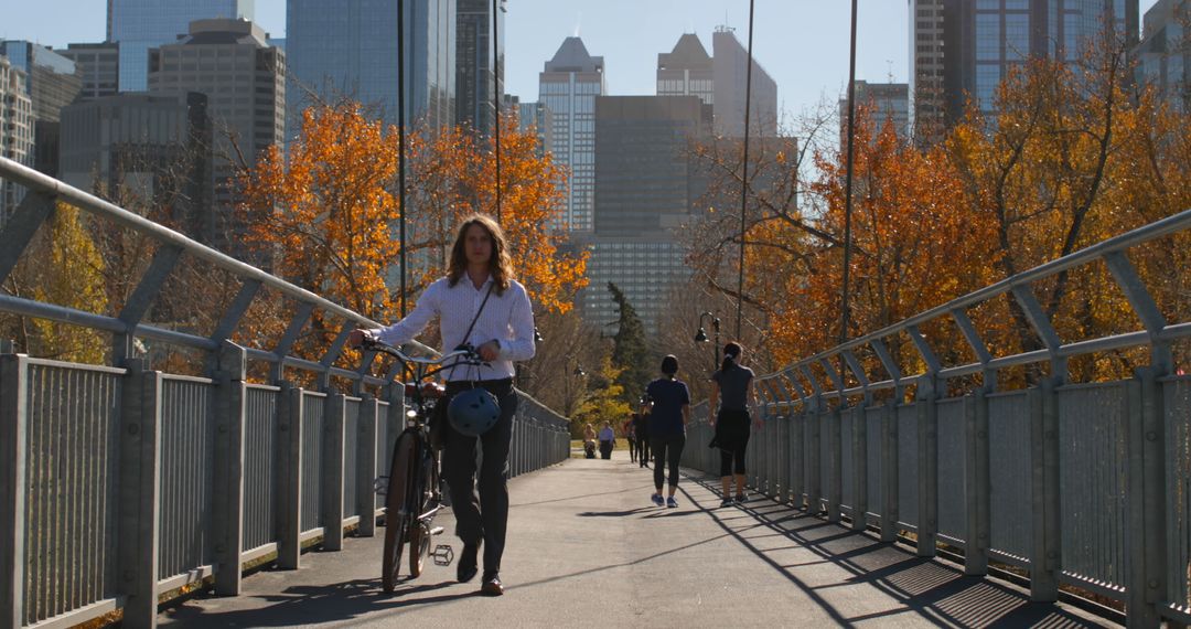 Woman Walking Bicycle on Urban Bridge with Autumn Foliage - Free Images, Stock Photos and Pictures on Pikwizard.com