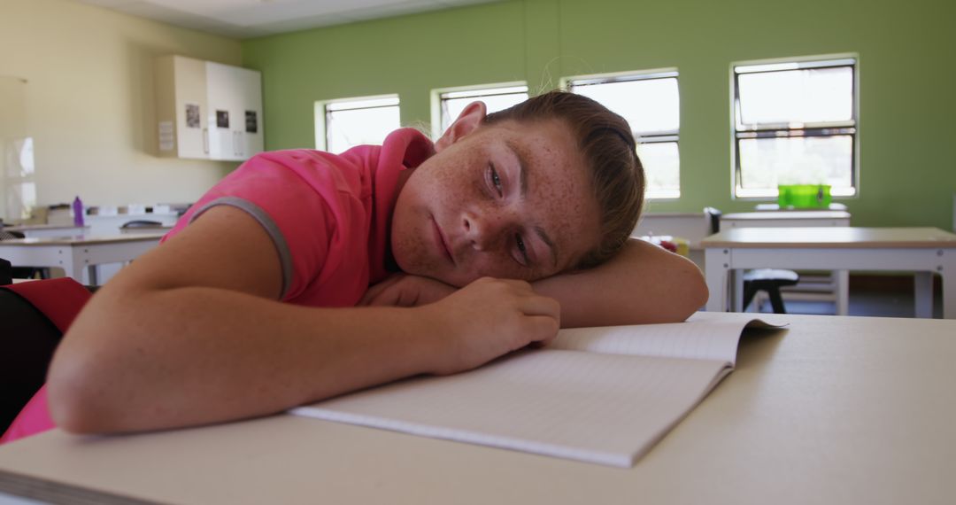 Tired Schoolboy Resting on Desk in Classroom