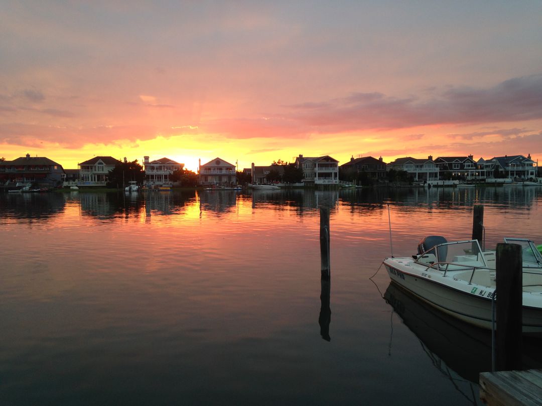 Serene Sunset Over Waterfront Homes With Boat Reflection - Free Images, Stock Photos and Pictures on Pikwizard.com