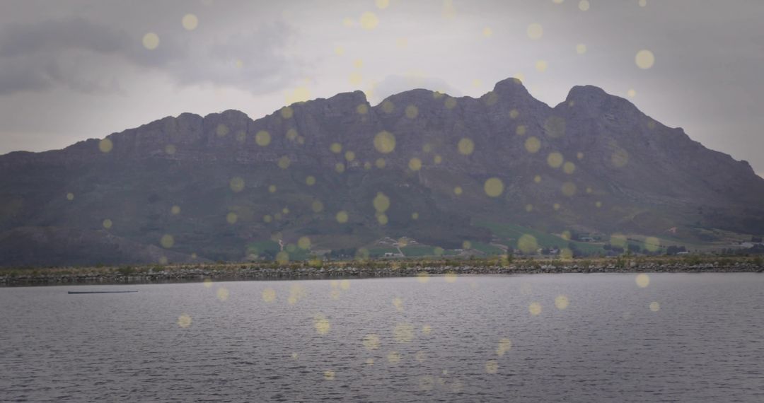 Undulating Mountain Ridge Over Calm Lake With Golden Bokeh Light Reflections
