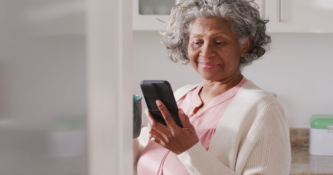 Senior Woman Using Smartphone Happily in Kitchen - Free Images, Stock Photos and Pictures on Pikwizard.com