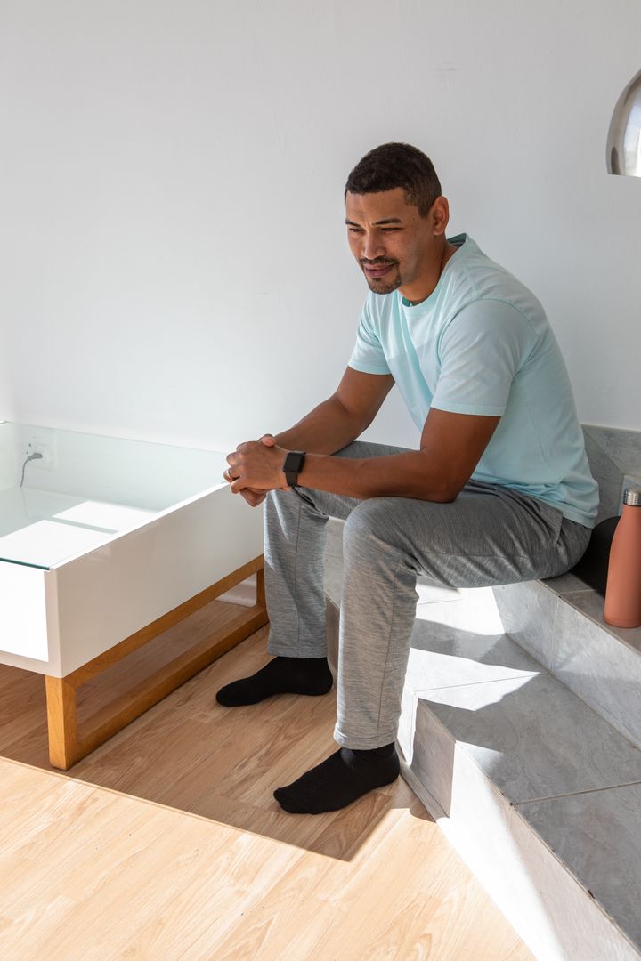 Male Relaxing at Home while Checking Smartwatch in Modern Minimalist Interior