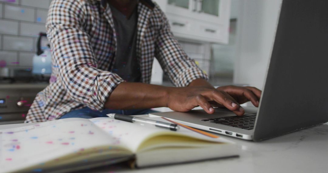 Man Working on Laptop in Home Office Kitchen Setting