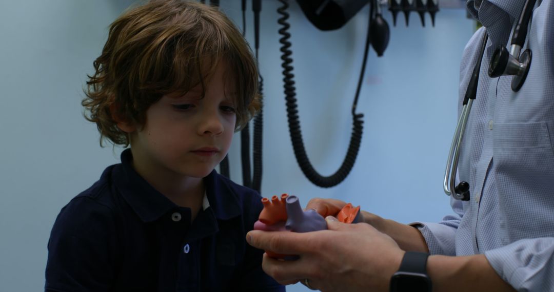 Worried young boy listening to doctor explain heart model during medical visit - Free Images, Stock Photos and Pictures on Pikwizard.com