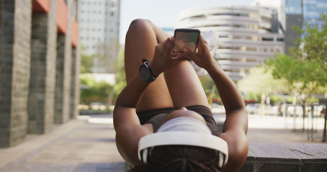 Young Woman Relaxing Outdoors with Smartphone and Headphones - Free Images, Stock Photos and Pictures on Pikwizard.com