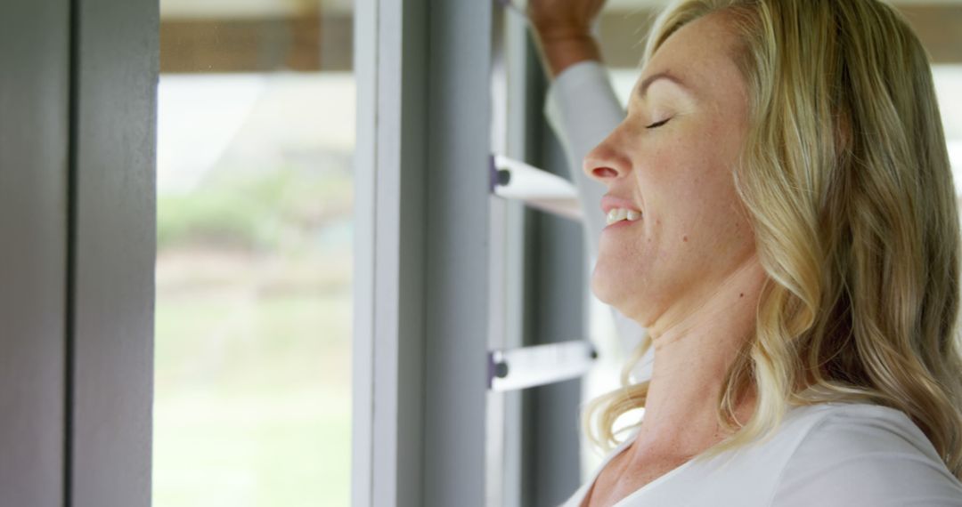 Blonde woman enjoying fresh air through window - Free Images, Stock Photos and Pictures on Pikwizard.com