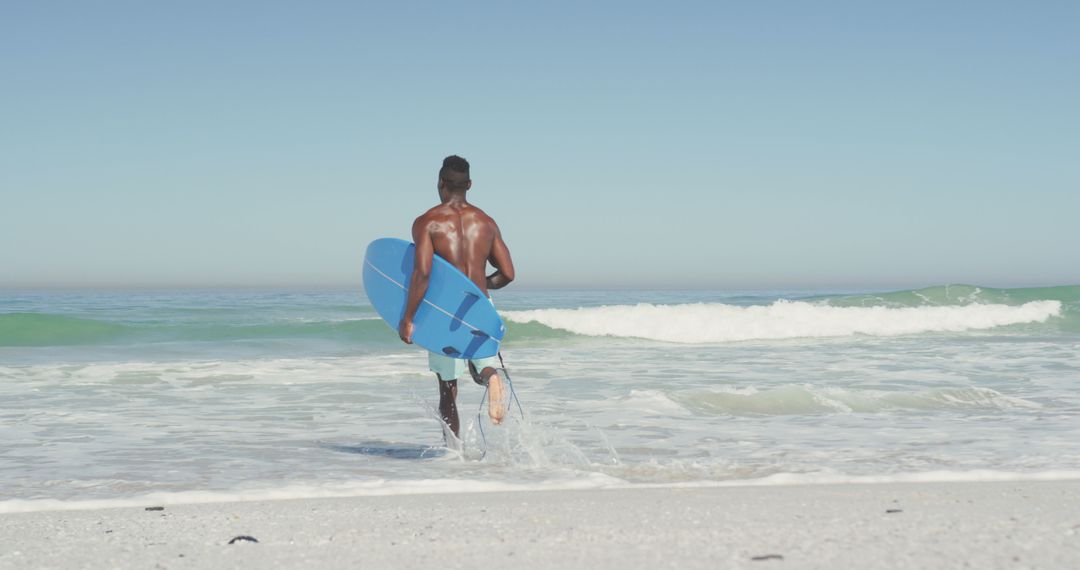 African american man running on sea and holding surfboard - Free Images, Stock Photos and Pictures on Pikwizard.com