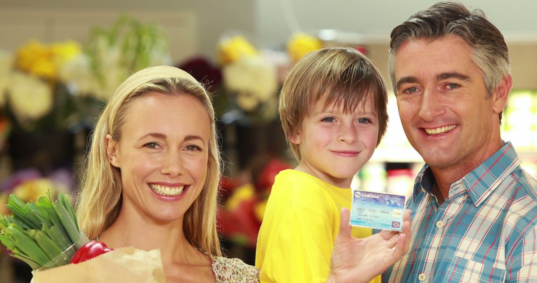 Happy family in grocery store holding credit card and shopping bags - Free Images, Stock Photos and Pictures on Pikwizard.com