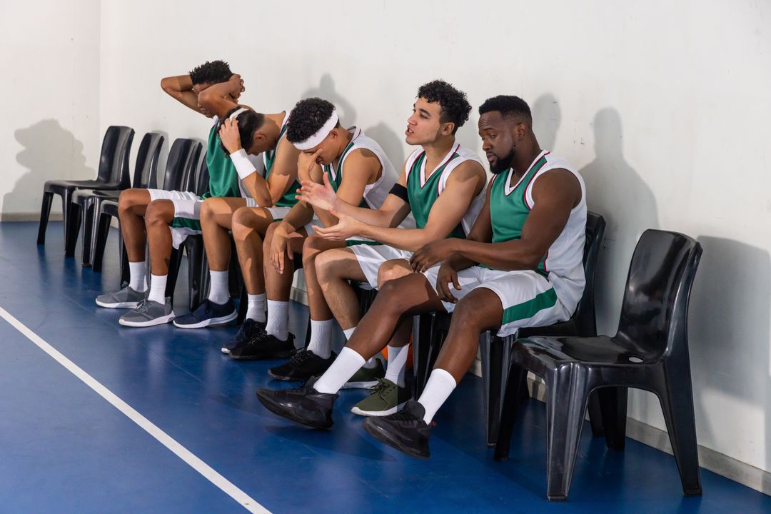 Diverse Basketball Team Resting on Sidelines in Gymnasium