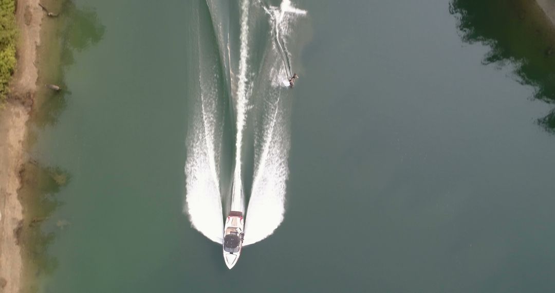 Aerial view of motorboat towing wakeboarder in serene lake - Free Images, Stock Photos and Pictures on Pikwizard.com