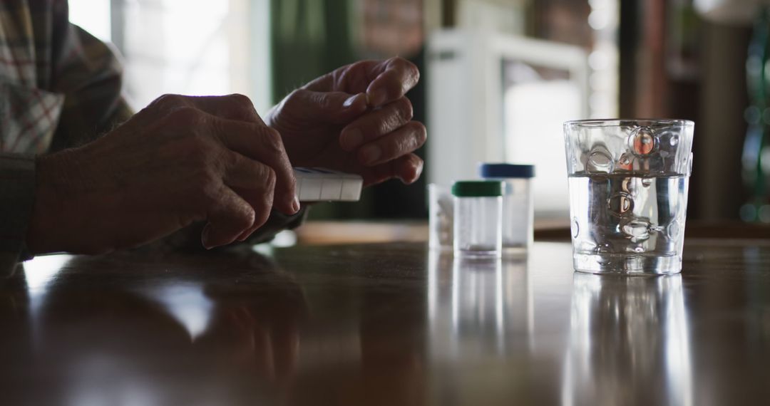 Elderly Person Organizing Medication with Capsules and Glass of Water - Free Images, Stock Photos and Pictures on Pikwizard.com