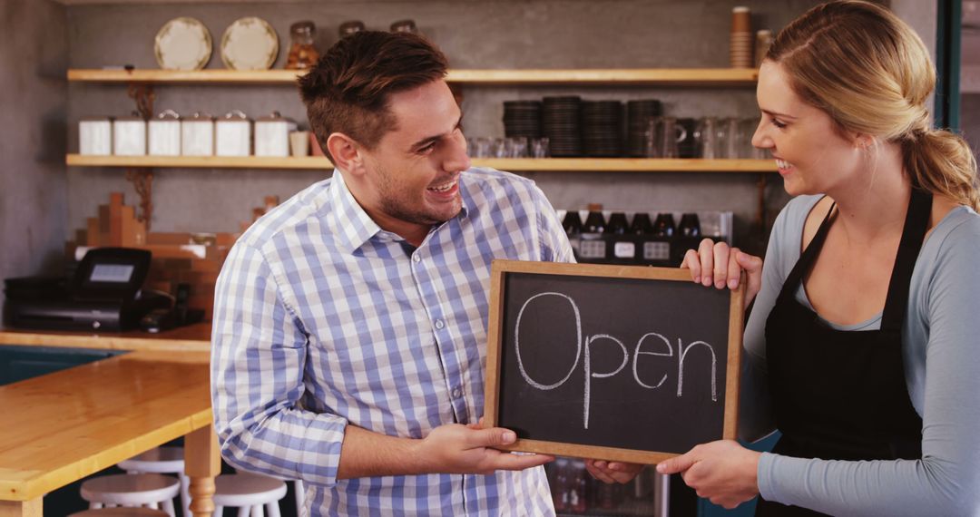 Café owners holding open sign with smiles in café interior - Free Images, Stock Photos and Pictures on Pikwizard.com