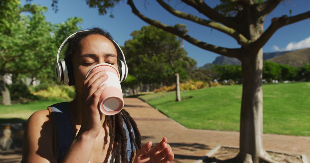 Young Woman Listening to Music and Sipping Coffee in Park - Free Images, Stock Photos and Pictures on Pikwizard.com