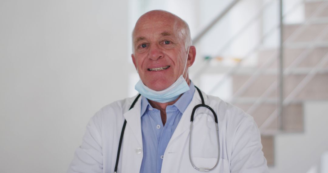 Senior male doctor smiling with stethoscope in a medical environment - Free Images, Stock Photos and Pictures on Pikwizard.com