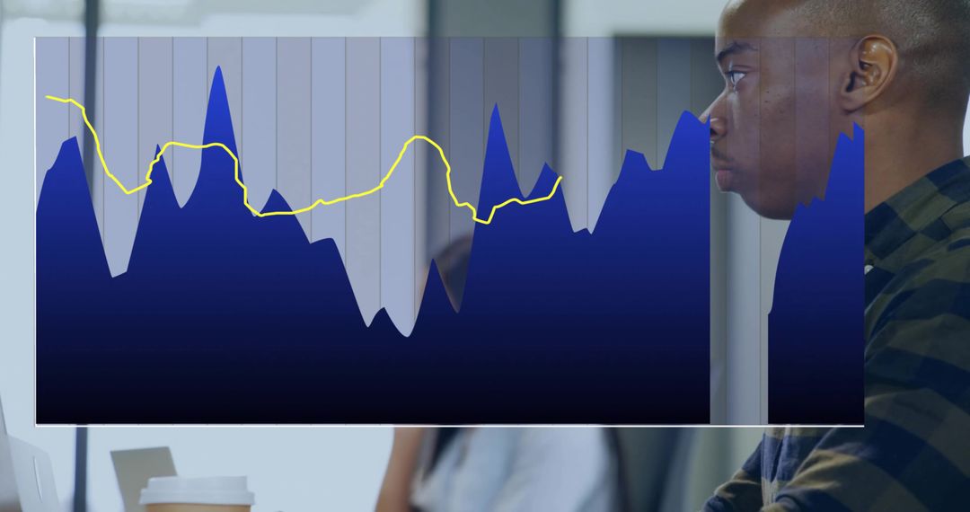 Professional analyzing area chart overlay while working at laptop in modern office