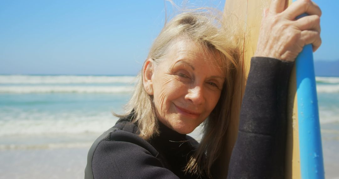 Smiling Senior Woman with Surfboard on Sunny Beach