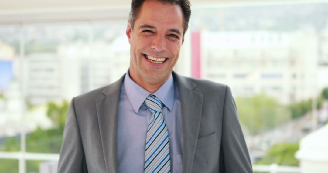 Smiling Businessman Wearing Gray Suit and Blue Tie During Workday - Free Images, Stock Photos and Pictures on Pikwizard.com