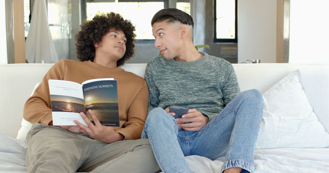 Smiling Men Relaxing with Book and Gamepad in Cozily Furnished Living Room