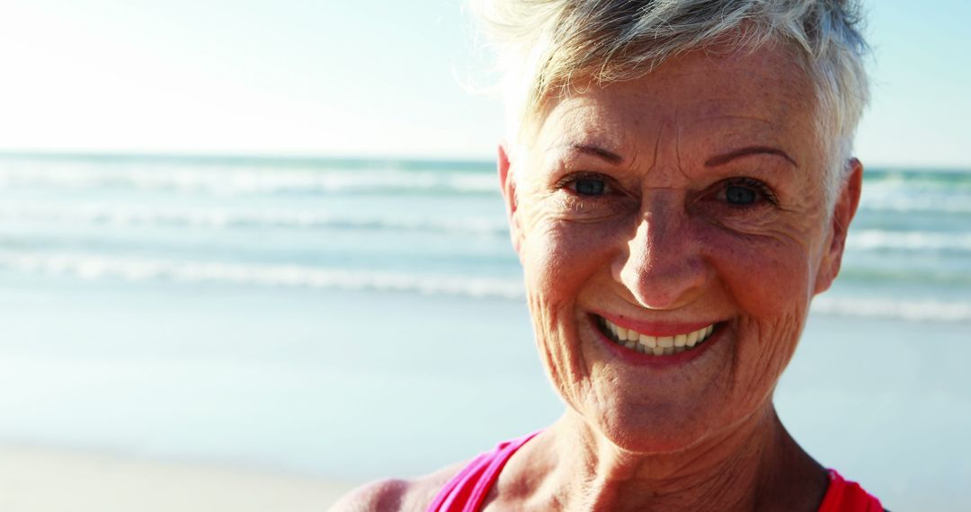 Smiling Senior Woman Enjoying Sunny Day at Beach - Free Images, Stock Photos and Pictures on Pikwizard.com