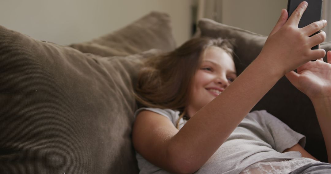 Happy Girl Relaxing on Couch, using Tablet, Smiling - Free Images, Stock Photos and Pictures on Pikwizard.com