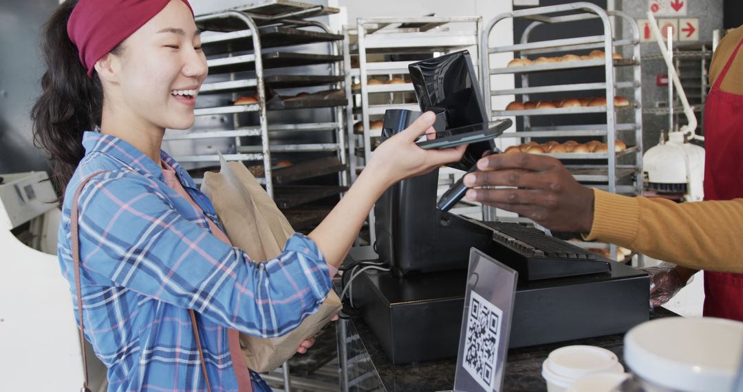 Smiling Woman Paying with Smartphone in Bakery - Free Images, Stock Photos and Pictures on Pikwizard.com