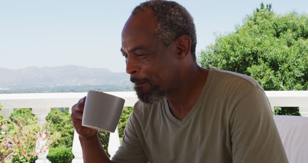 Senior african american man drinking coffee while sitting in the balcony at home - Free Images, Stock Photos and Pictures on Pikwizard.com