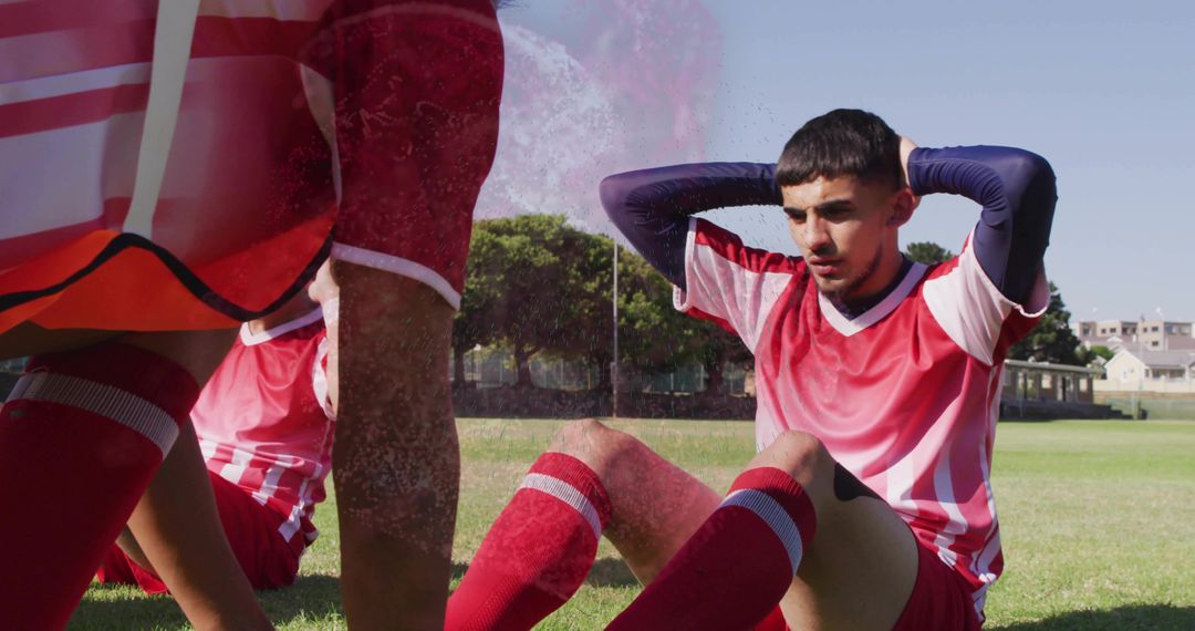 Young Soccer Player in Red Kit Doing Sit-Ups on Field
