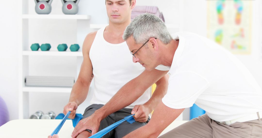 Physiotherapist assisting male patient with resistance band exercise - Free Images, Stock Photos and Pictures on Pikwizard.com