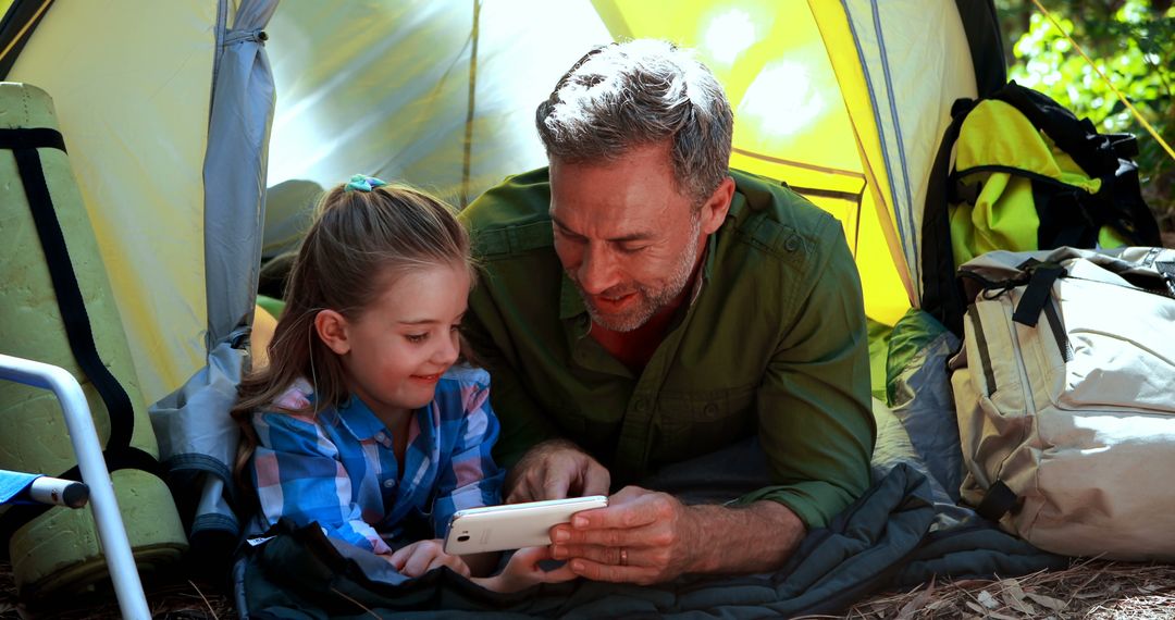 Father and Daughter Enjoying Time Together in Tent Watching Video on Tablet - Free Images, Stock Photos and Pictures on Pikwizard.com