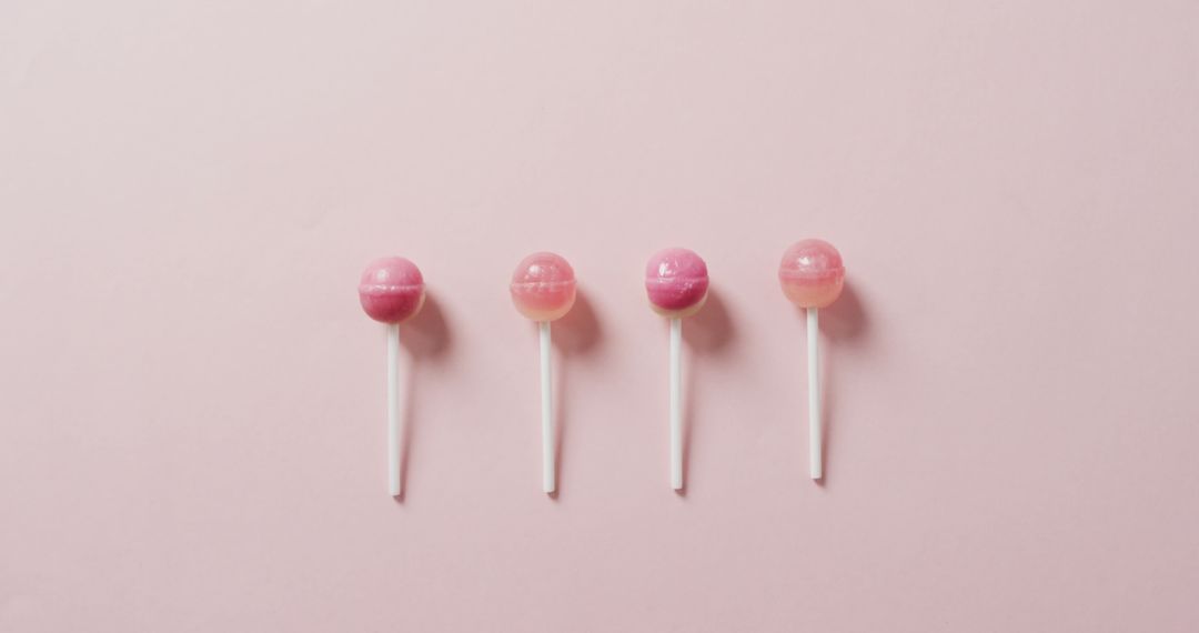 Pink Lollipops Aligned in a Row on Light Pink Background - Free Images, Stock Photos and Pictures on Pikwizard.com