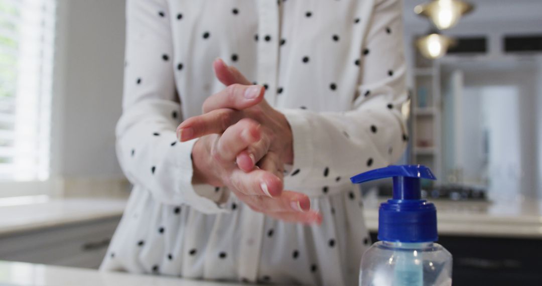 Woman Cleaning Hands with Hand Sanitizer in Kitchen - Free Images, Stock Photos and Pictures on Pikwizard.com