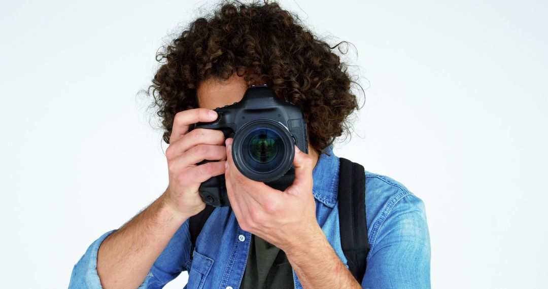 Young Man with Curly Hair Holding Professional Camera - Free Images, Stock Photos and Pictures on Pikwizard.com