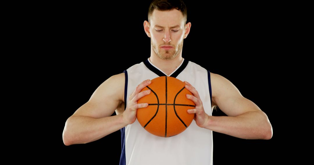 Determined Basketball Player Holding Ball Against Black Background - Free Images, Stock Photos and Pictures on Pikwizard.com