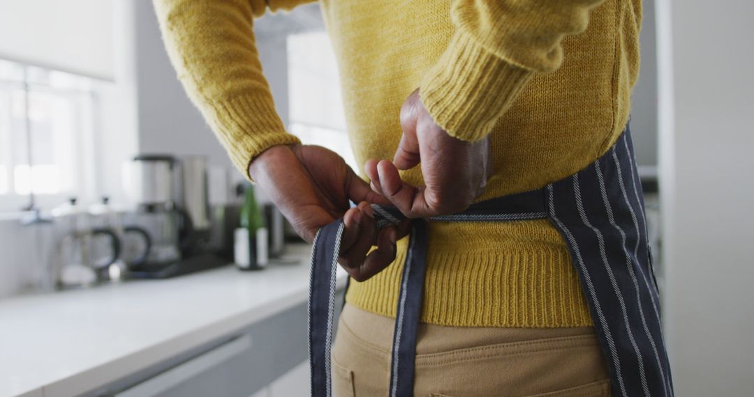 Person tying apron's strings in modern kitchen - Free Images, Stock Photos and Pictures on Pikwizard.com