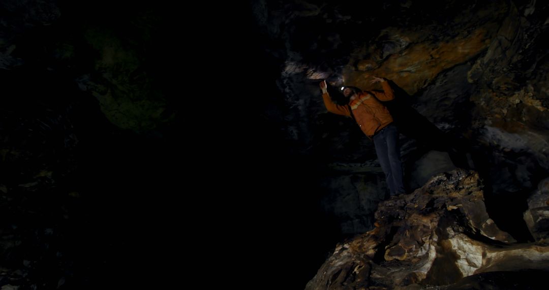 Caucasian man wearing headlamp exploring dark cave system touching cave ceiling, copy space - Free Images, Stock Photos and Pictures on Pikwizard.com