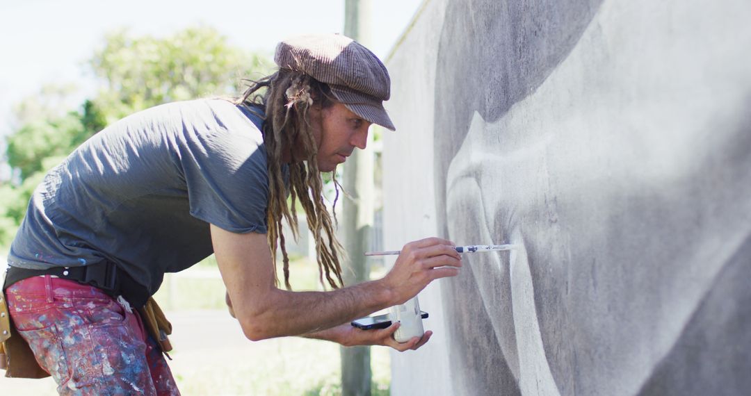Image of caucasian male artist with dreadlocks painting whale mural on wall - Free Images, Stock Photos and Pictures on Pikwizard.com