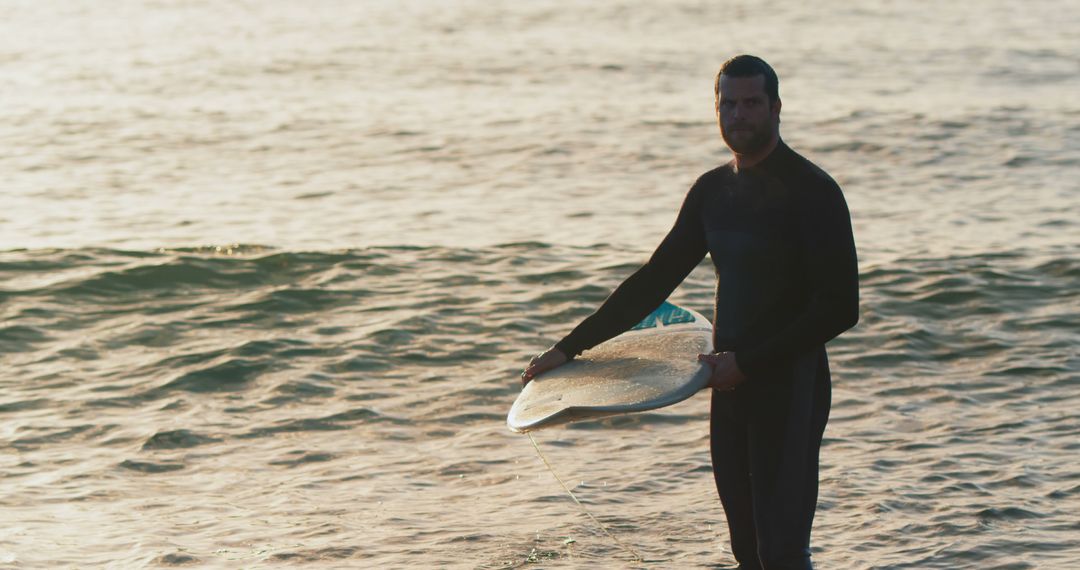 Male Surfer Standing with Surfboard in Sunset Waves - Free Images, Stock Photos and Pictures on Pikwizard.com