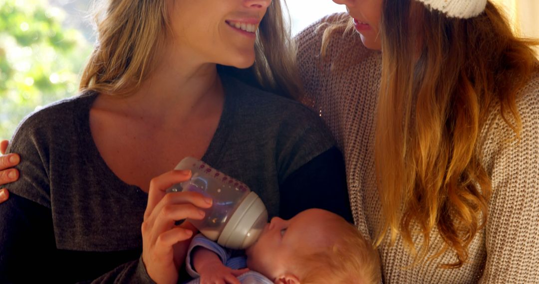 Two women caretakers feeding newborn baby with bottle - Free Images, Stock Photos and Pictures on Pikwizard.com