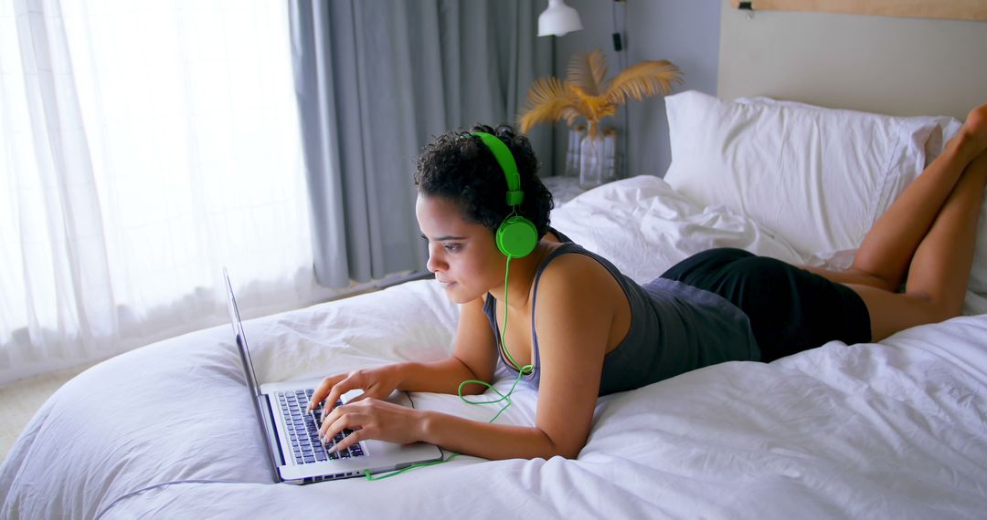 Young Woman with Headphones Using Laptop on Bed - Free Images, Stock Photos and Pictures on Pikwizard.com