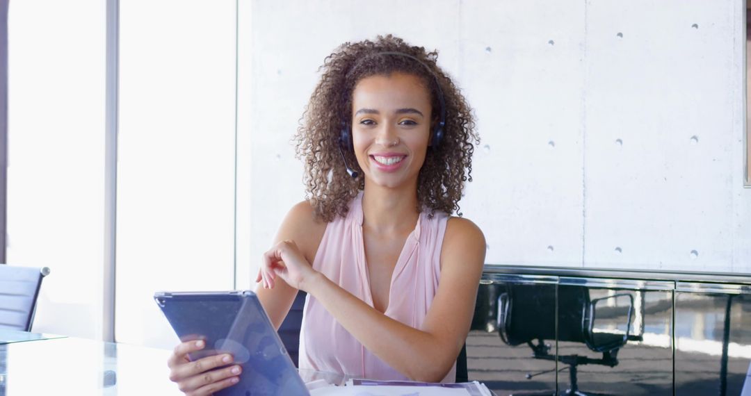 Professional Woman Smiling at Desk with Tablet and Headset