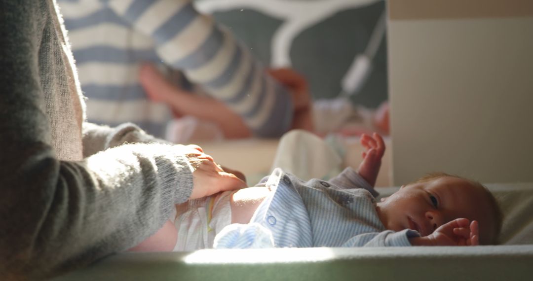 Mother Changing Newborn's Diaper in Sunlit Room - Free Images, Stock Photos and Pictures on Pikwizard.com