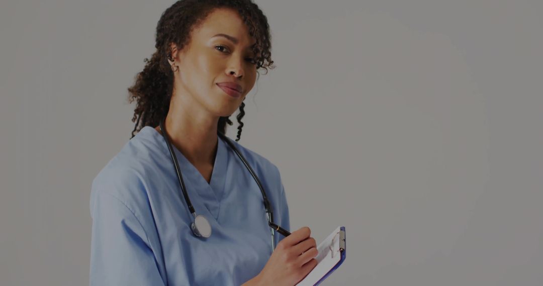 Smiling Nurse Writing in Clinic with Clipboard and Stethoscope