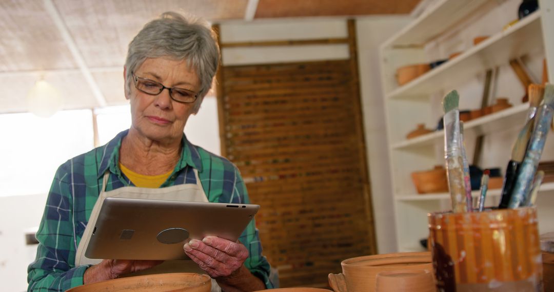 Senior Woman Using Digital Tablet in Pottery Studio - Free Images, Stock Photos and Pictures on Pikwizard.com