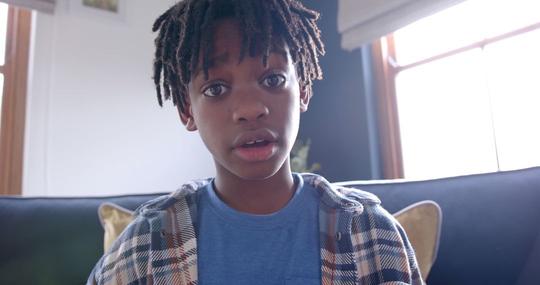 Curious Young Boy with Dreadlocks Sitting Indoors - Free Images, Stock Photos and Pictures on Pikwizard.com