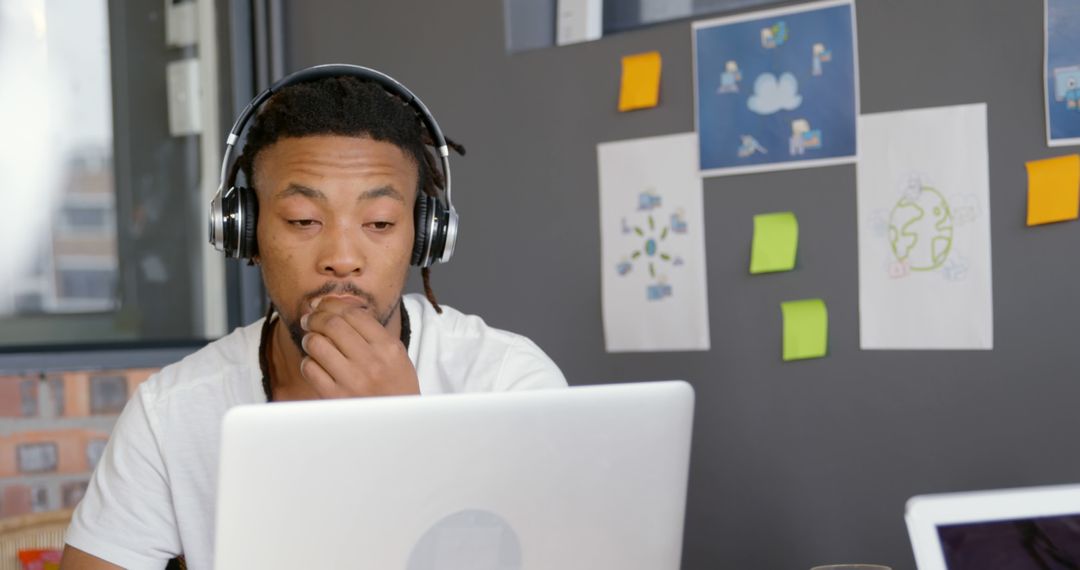 Focused Young Man Working on Laptop Wearing Headphones in Office - Free Images, Stock Photos and Pictures on Pikwizard.com