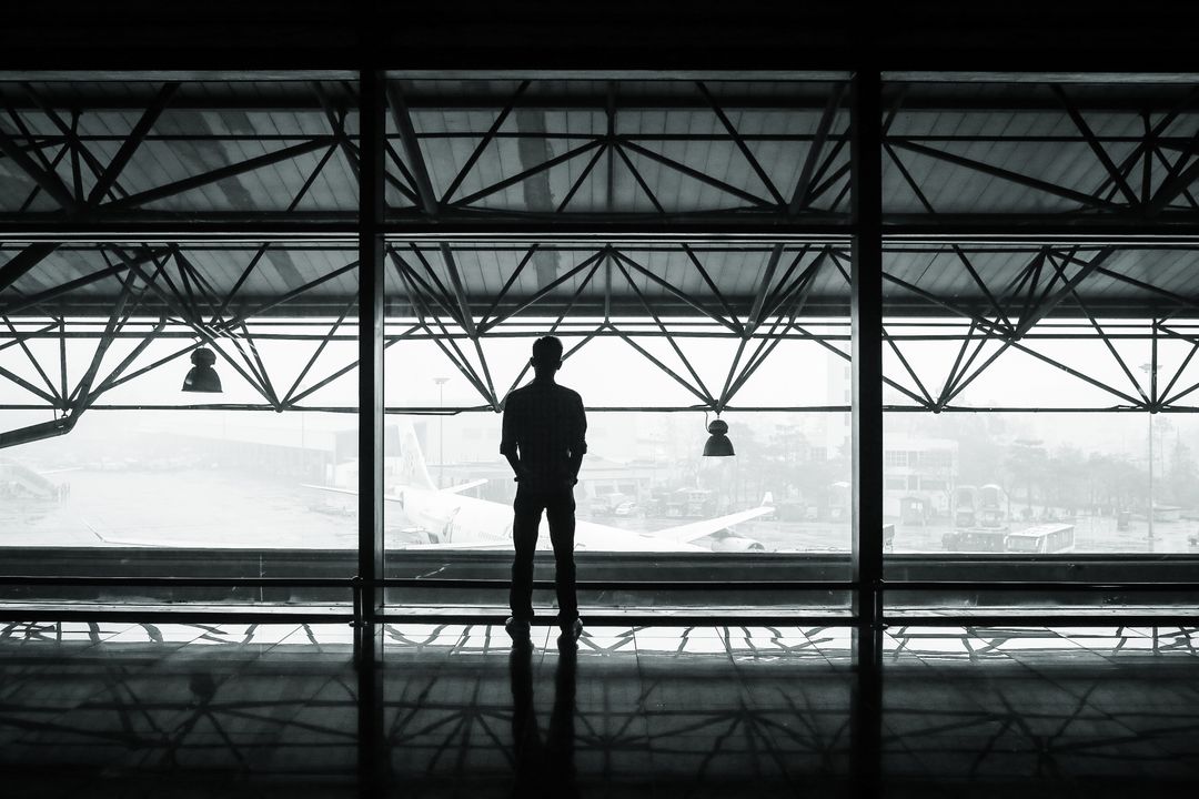 Silhouette of Person Looking Out at Airport Terminal - Free Images, Stock Photos and Pictures on Pikwizard.com