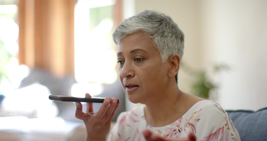 Senior Woman Using Voice Command on Smartphone at Home