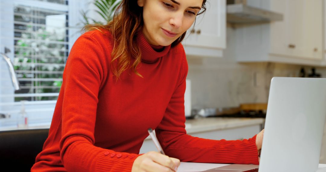 Woman in Red Sweater Working on Laptop at Kitchen Table - Free Images, Stock Photos and Pictures on Pikwizard.com