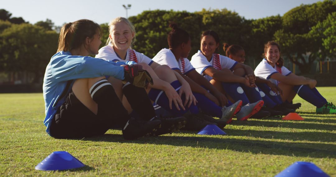 Smiling Female Soccer Players Resting on Grass Field During Soccer Practice - Free Images, Stock Photos and Pictures on Pikwizard.com